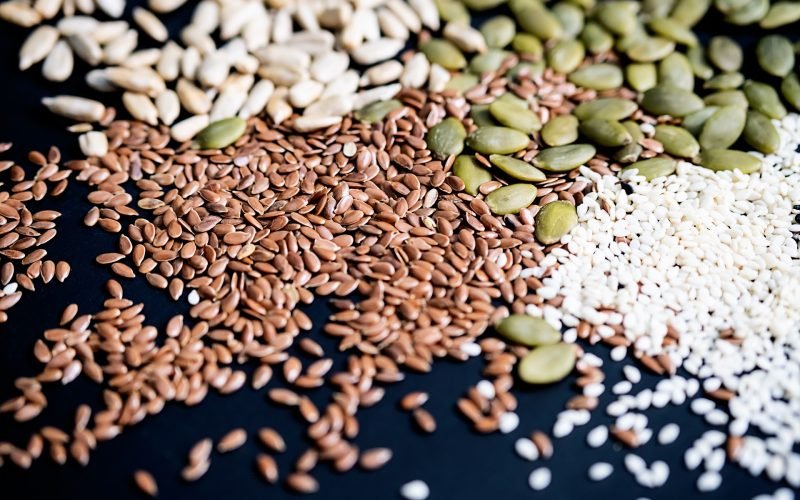 Various seed on the black. Flax, sesame, sunflower and pumpkin seed, close up.
